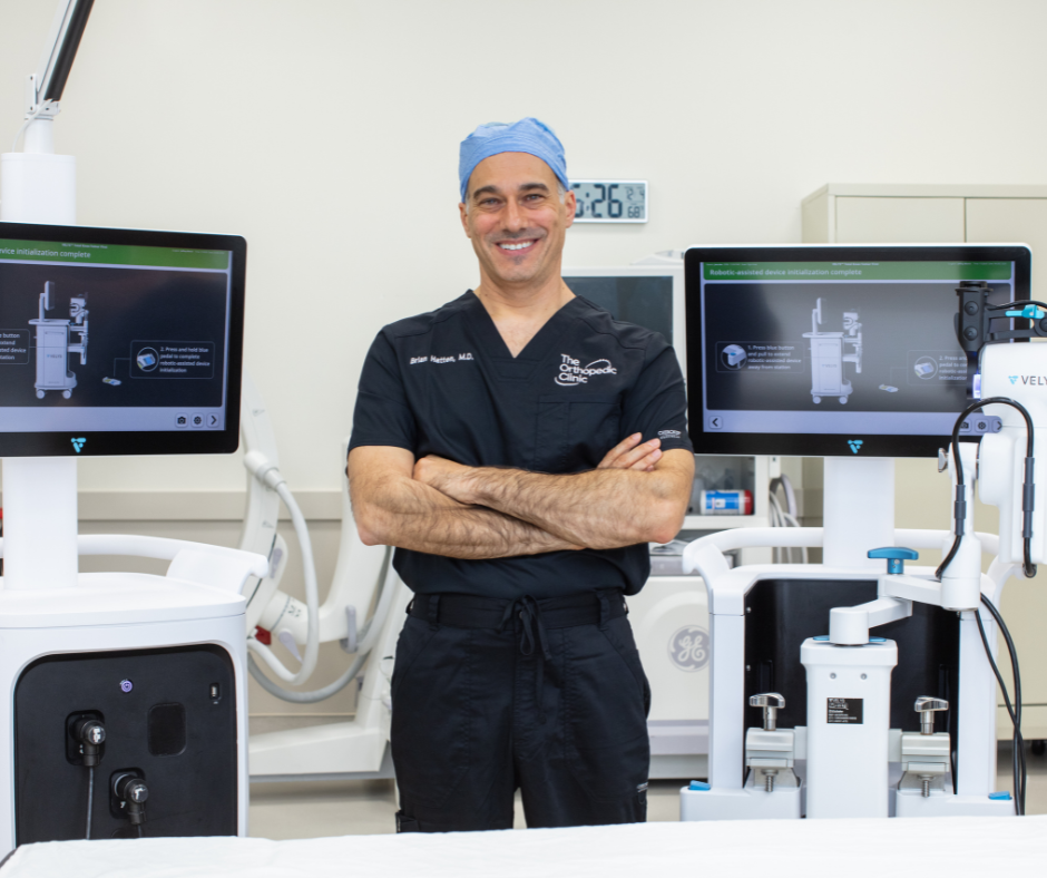 Dr. Hatten standing with the VELYS robotic-assisted surgical system at The Orthopedic Clinic Surgery Center